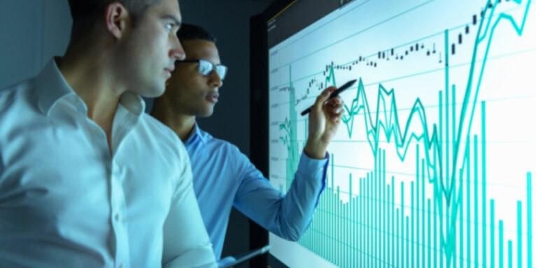 Businessmen studying graphs on an interactive screen in business meeting