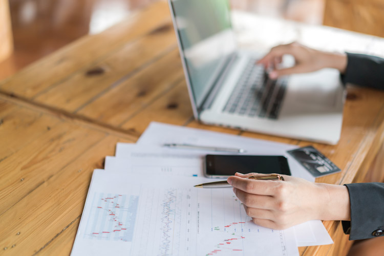 Business woman hand with Financial charts and laptop on the tabl Alianza entre ADP y Convera