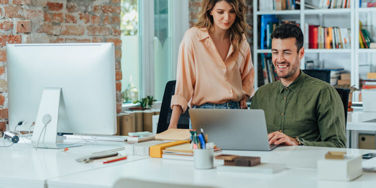 Happy Business People Using a Laptop Computer Together at the Office Roles TI