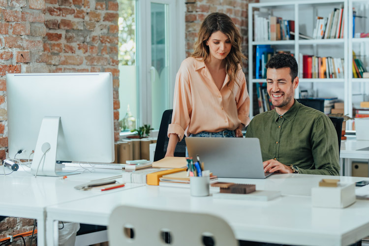 Happy Business People Using a Laptop Computer Together at the Office Roles TI