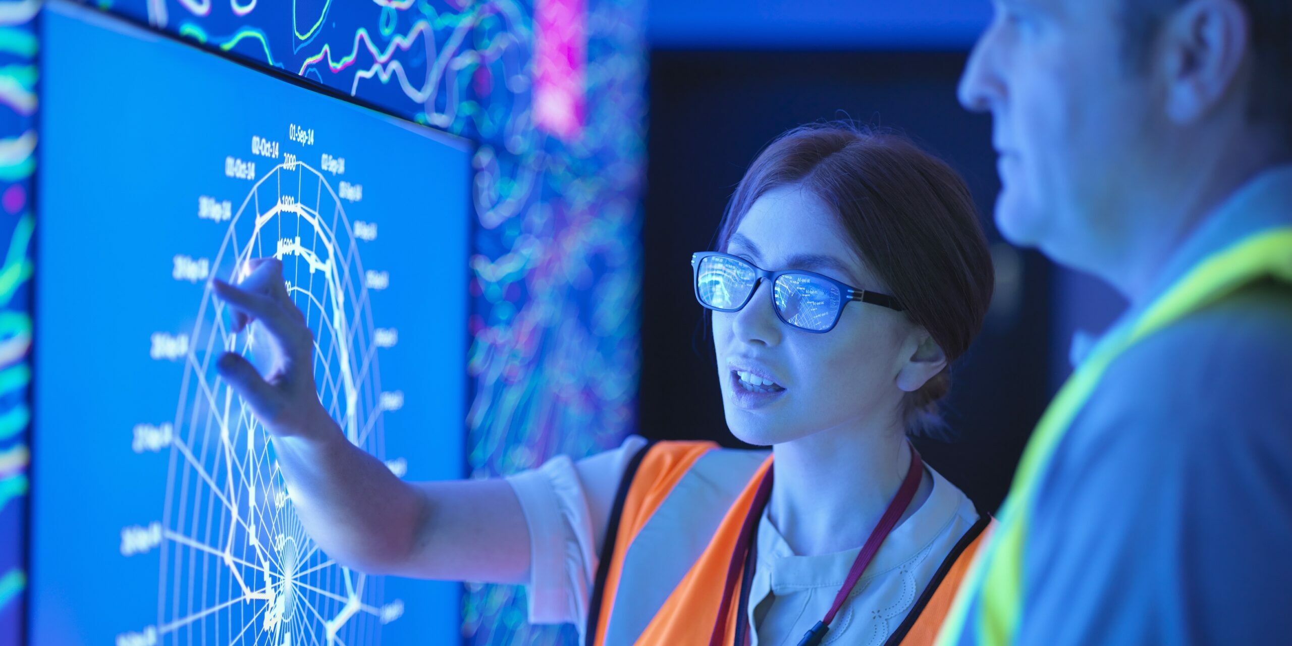 Female geologist with colleague studying graphical display of oil and gas bearing rock on screens Hitachi iQ