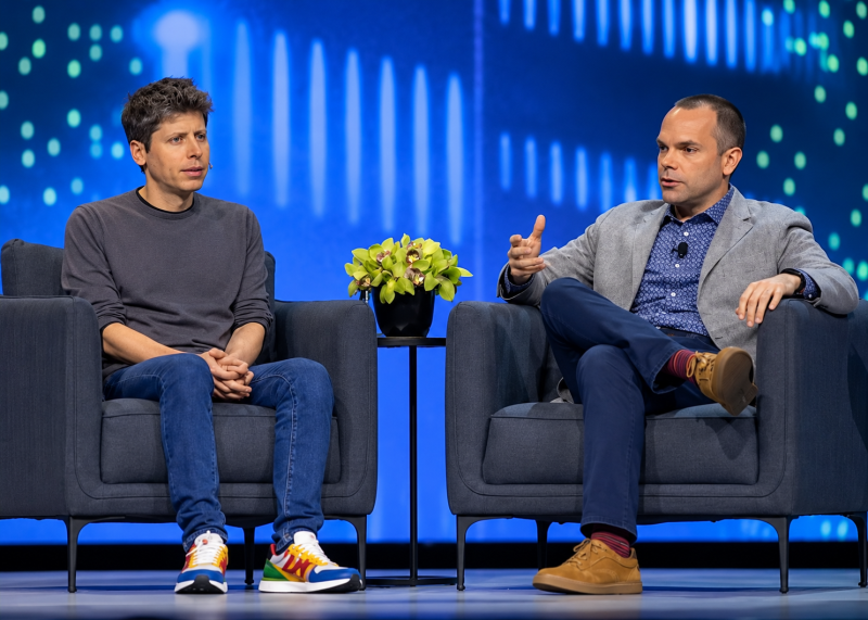 Entrevista tecnológica en escenario azul Sam Altman y Clay Magouyrk conversan durante Oracle AI World en Las Vegas.